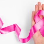 Roze lintje symbool voor vroegtijdige diagnose van borstkanker in geopende hand op witte achtergrond