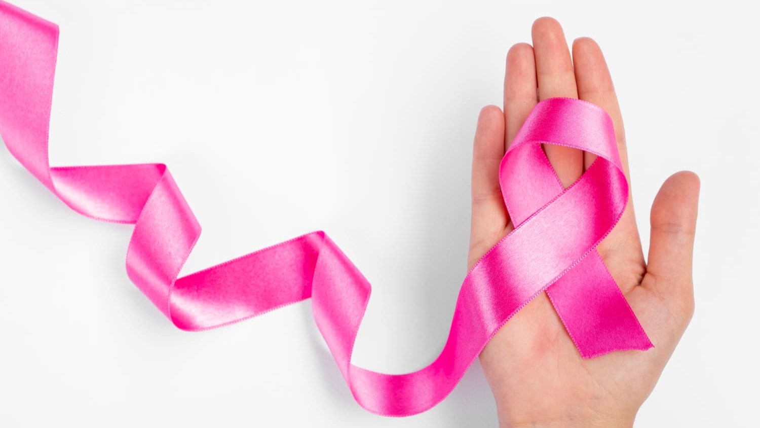 Roze lintje symbool voor vroegtijdige diagnose van borstkanker in geopende hand op witte achtergrond