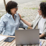 2 vrouwen praten met elkaar achter een laptop