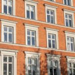 Gerenoveerde houten kozijnen in een klassiek rood bakstenen appartementencomplex