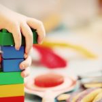 Kind stapelt kleurrijke bouwstenen tijdens kleinschalige opvang bij een gastouder