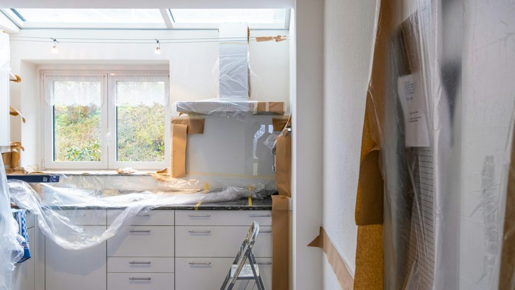 Keuken in renovatie met afgedekte kasten en apparatuur tijdens verbouwingswerkzaamheden