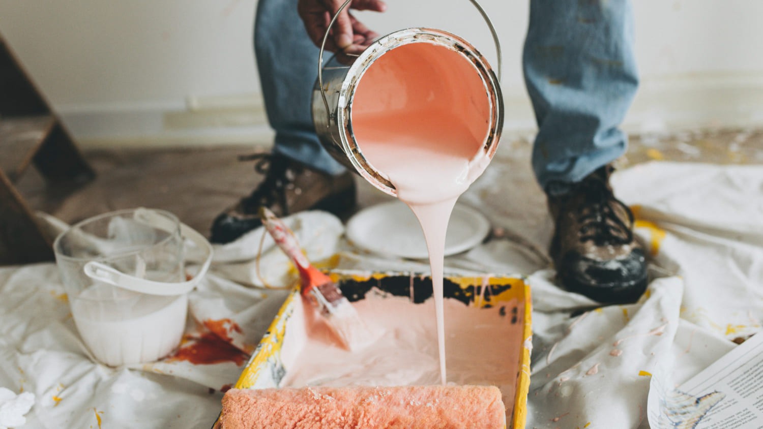 Verf wordt in een bak gegoten om muren te schilderen als onderdeel van periodiek onderhoud.