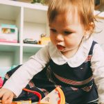 Peuter speelt met speelgoed op vloer in huiselijke opvangomgeving