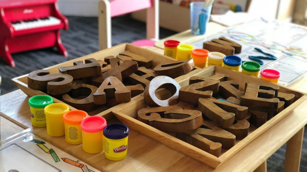 Houten letters en kleurrijke klei op tafel in speelhoek voor kinderen