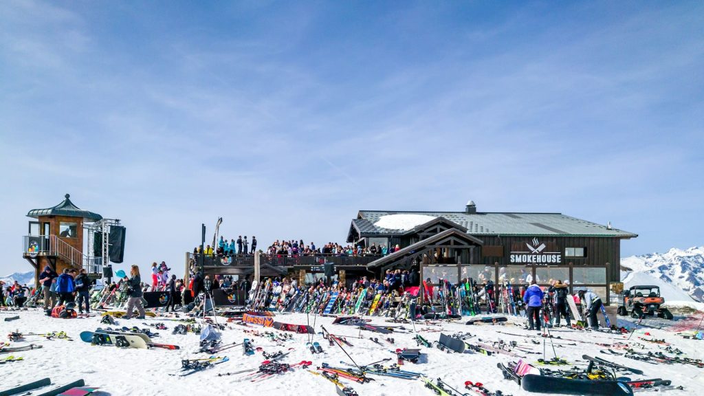 Druk terras op de piste tijdens eerste skidagen met ski’s in de sneeuw en mensen in de zon