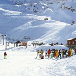 Ski&euml;rs op brede piste tijdens eerste skidagen met lift en besneeuwde bergen op de achtergrond